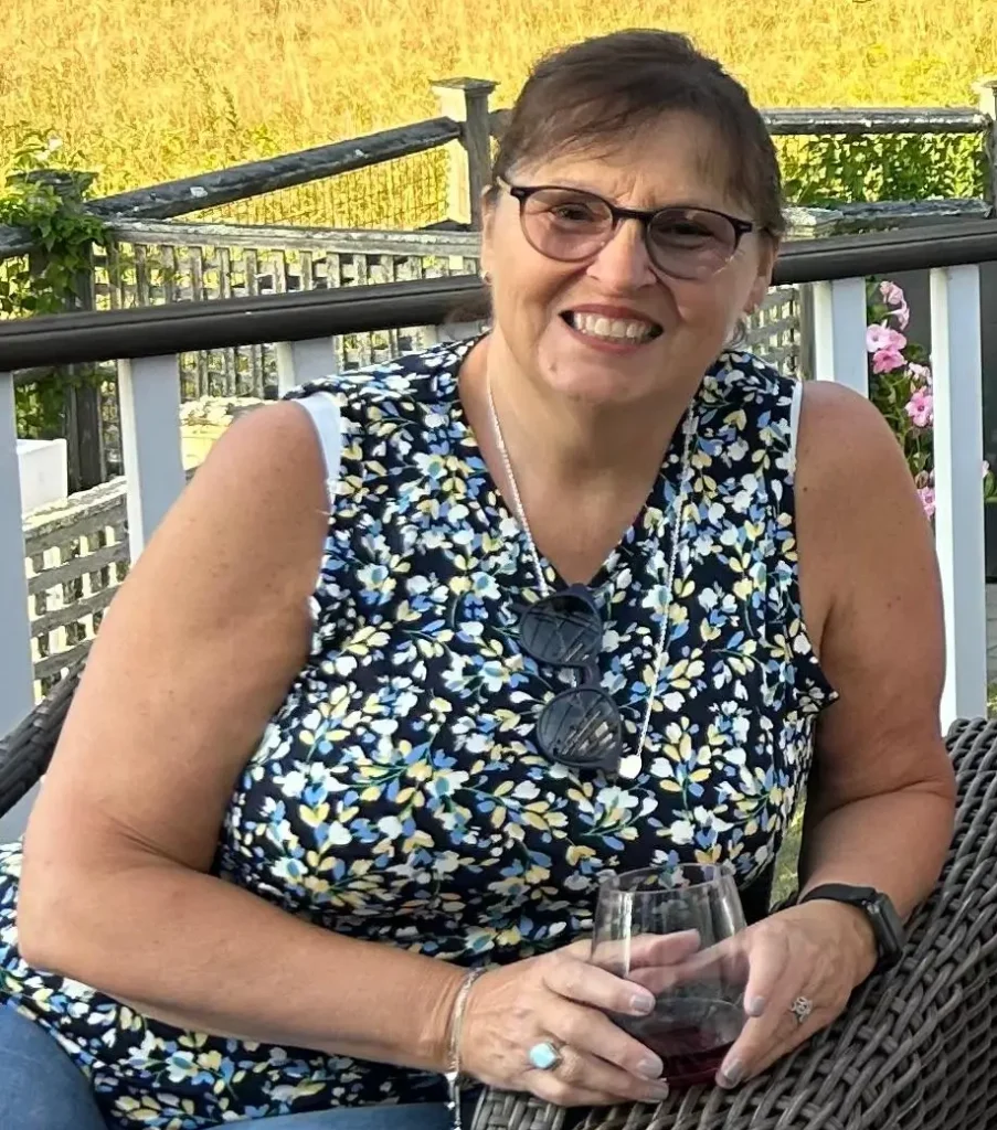 Robin A. Gillette seated outdoors smiling beside a waterfront railing